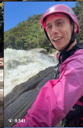 Cliente sorrindo de capacete, com cachoeira ao fundo