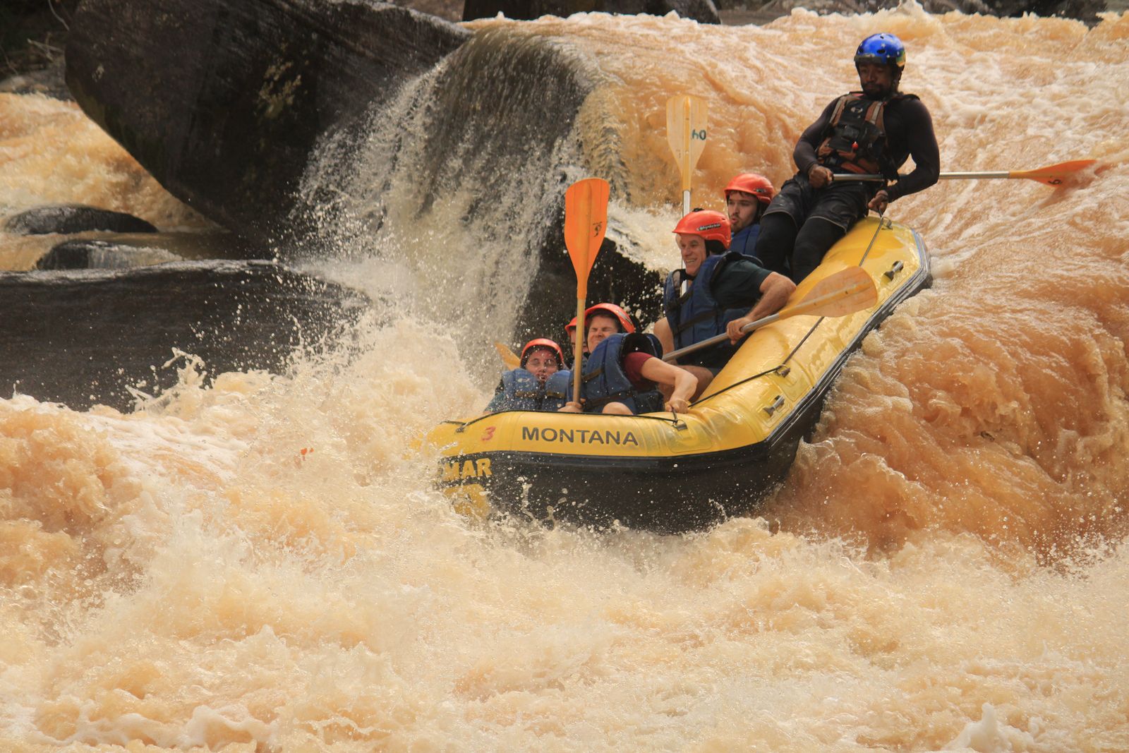 Bote da Montana descendo uma queda d'água ao lado de uma pedra grande no Alto Braz