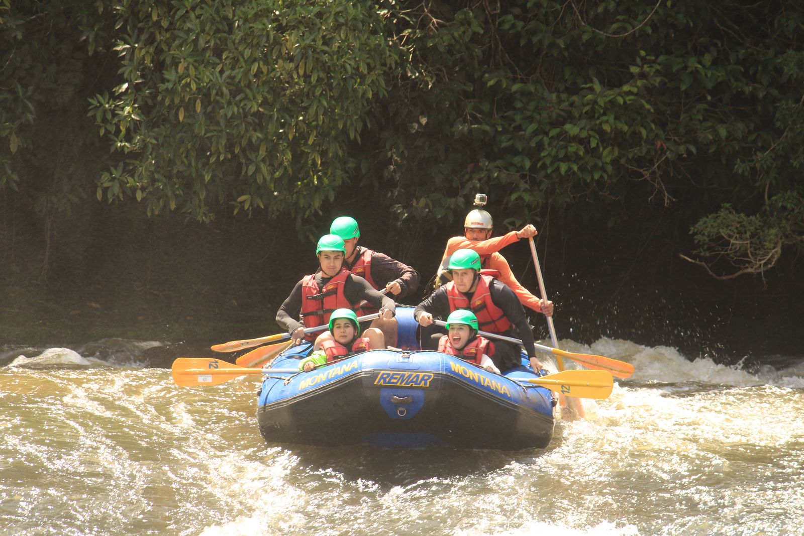 Turma remando no bote azul da Montana com a mata fechada do Santa Virgínia ao fundo